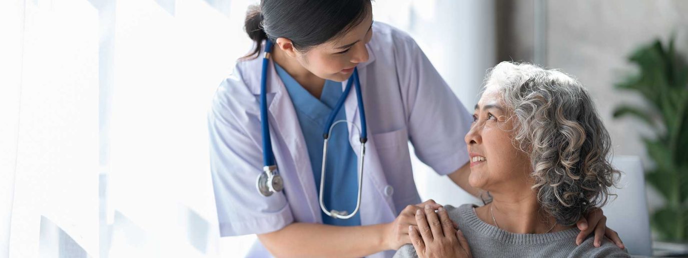 nurse supporting older female Asian patient
