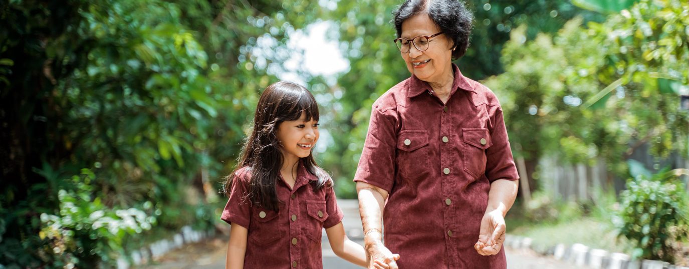 Mother and daughter holding hands and walking down tree lined lane