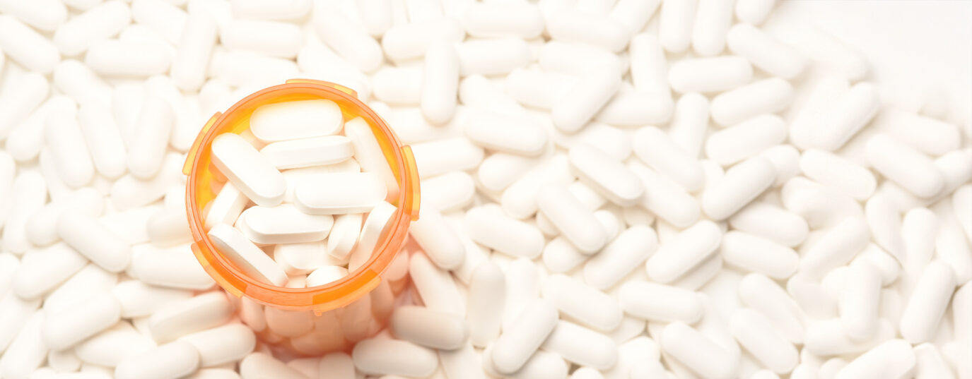 High angle view of a prescription bottled filled with pills surrounded by more of the same tablets