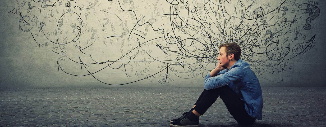 man sat on floor with illustrated thoughts and question marks coming from his head