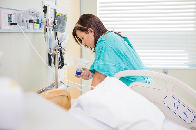 Pregnant woman undergoing a contraction using gas to ease the pain