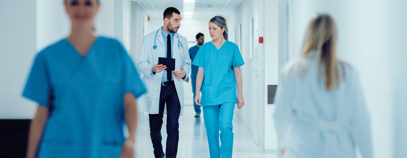 male and female doctor walking down a hospital corridor talking
