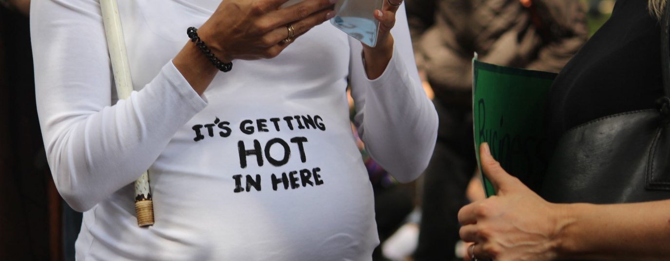 Pregnant woman wearing t-shirt saying 'it's getting hot in here'
