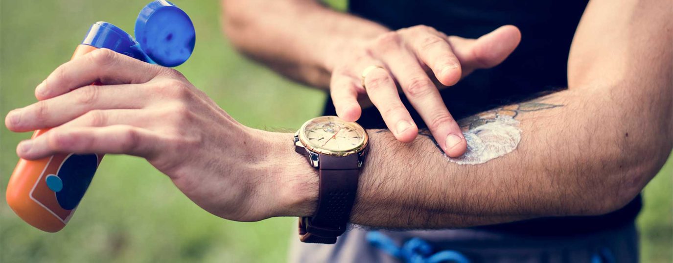 man putting suncream on forearm