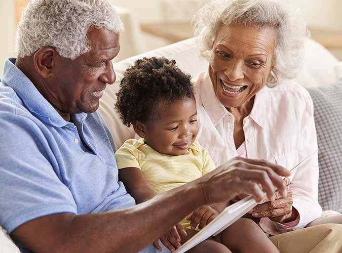 Black grandparents reading a book with their grandchild