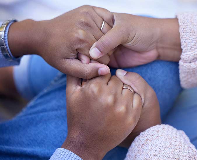 Two black women's hands holding each other's in a supportive way